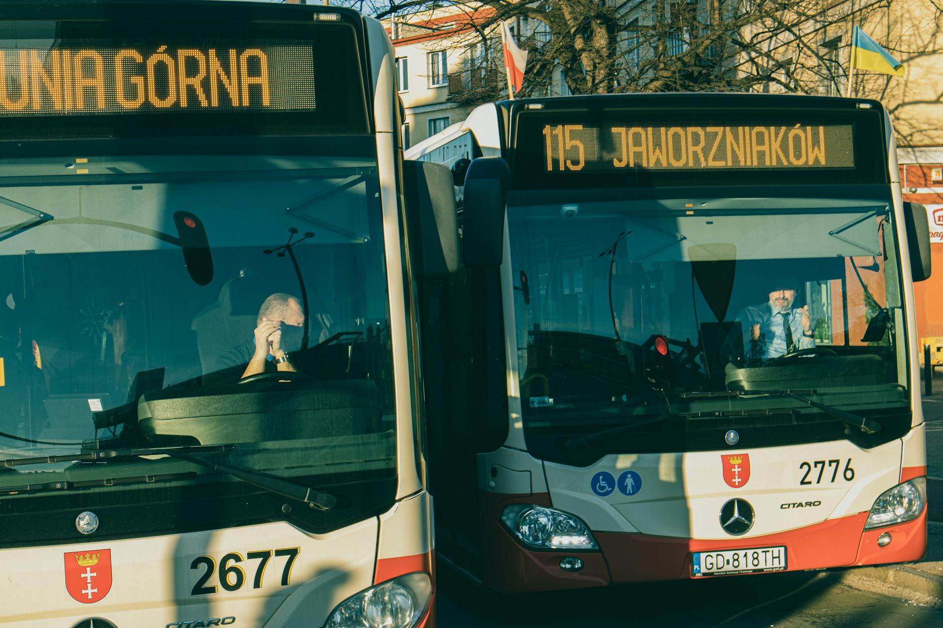 Ilustracja przedstawiająca autobus miejski na tle miasta Bolesławiec, symbolizująca przetarg na zakup autobusów.
